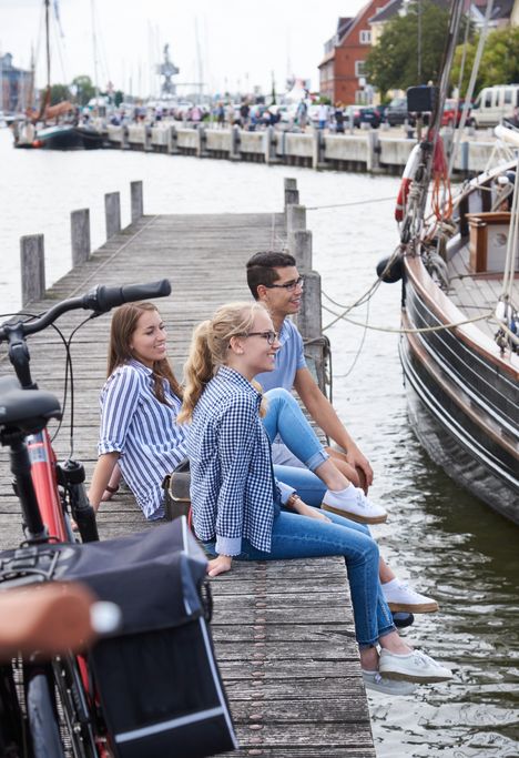 Gruppe von Freunden macht eine Fahrradtour und genießt eine Pause am Glückstädter Hafen.