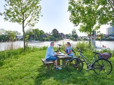 Paar ist mit dem Fahrrad an der Stör unterwegs und macht eine Pause auf einem Rastplatz mit Blick aufs Wasser.