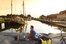 Paar ist mit dem Fahrrad unterwegs, macht am Hafenkopf in Glückstadt Pause und genießt den Blick aufs Wasser bei Sonnenuntergang.