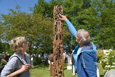 Eine Frau besucht den Skulpturenpark auf der Schlossinsel Barmstedt und lässt sich von einem Künstler über ein Ausstellungsstück informieren.