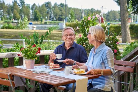 Ein Paar genießt eine Auszeit am Nord-Ostsee-Kanal mit leckerem Kaffee und Kuchen.