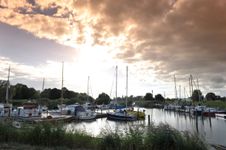 Blick auf einen kleinen Hafen an der Stör. Mehrere Segelschiffe liegen im Hafen.