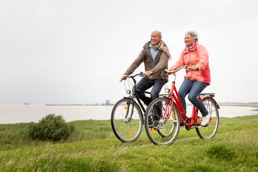 Ein paar ist am Elbdeich bei Glückstadt mit dem Fahrrad unterwegs und lässt sich den Wind um die Nase wehen.