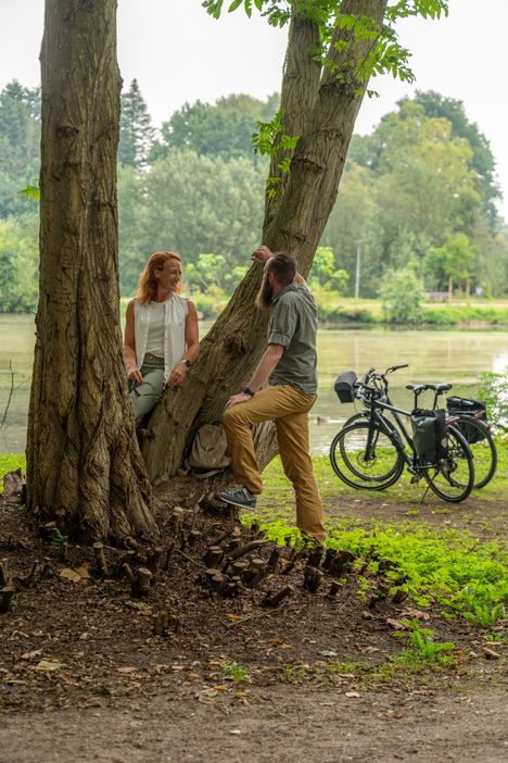 Ein Paar ist mit dem Fahrrad im Kurpark Bad Bramstedt unterwegs und genießt eine Pause an einem Teich.