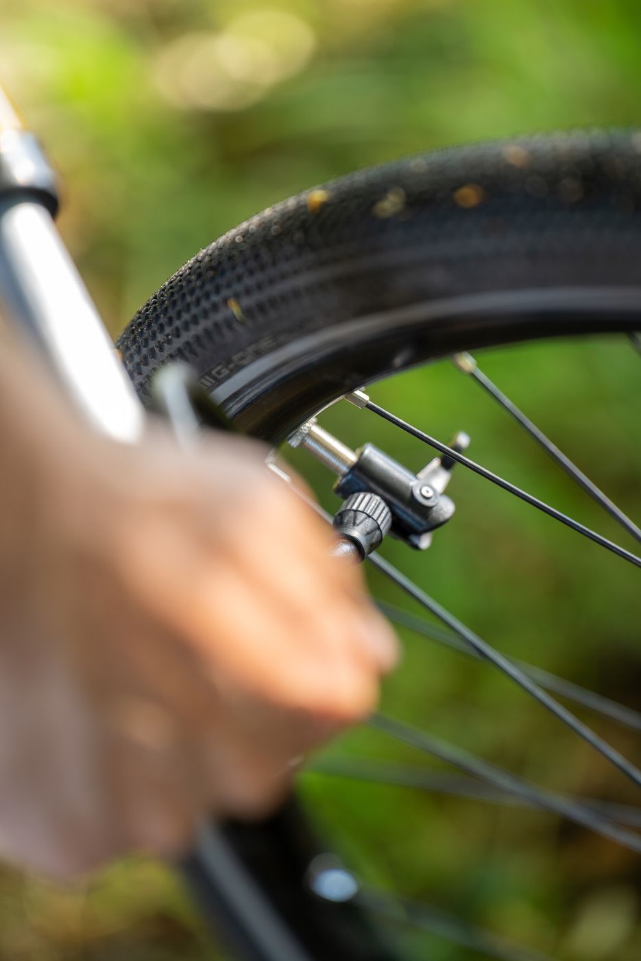 Ein Radfahrer pumpt den Fahrradreifen auf. Zusehen ist das Ventil und die Pumpe.