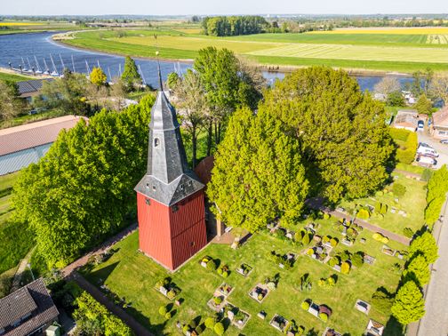 Luftaufnahme von der Kirche in Beidenfleth am Mönchsweg. Im Hintergrund ist die Störlandschaft zu sehen.