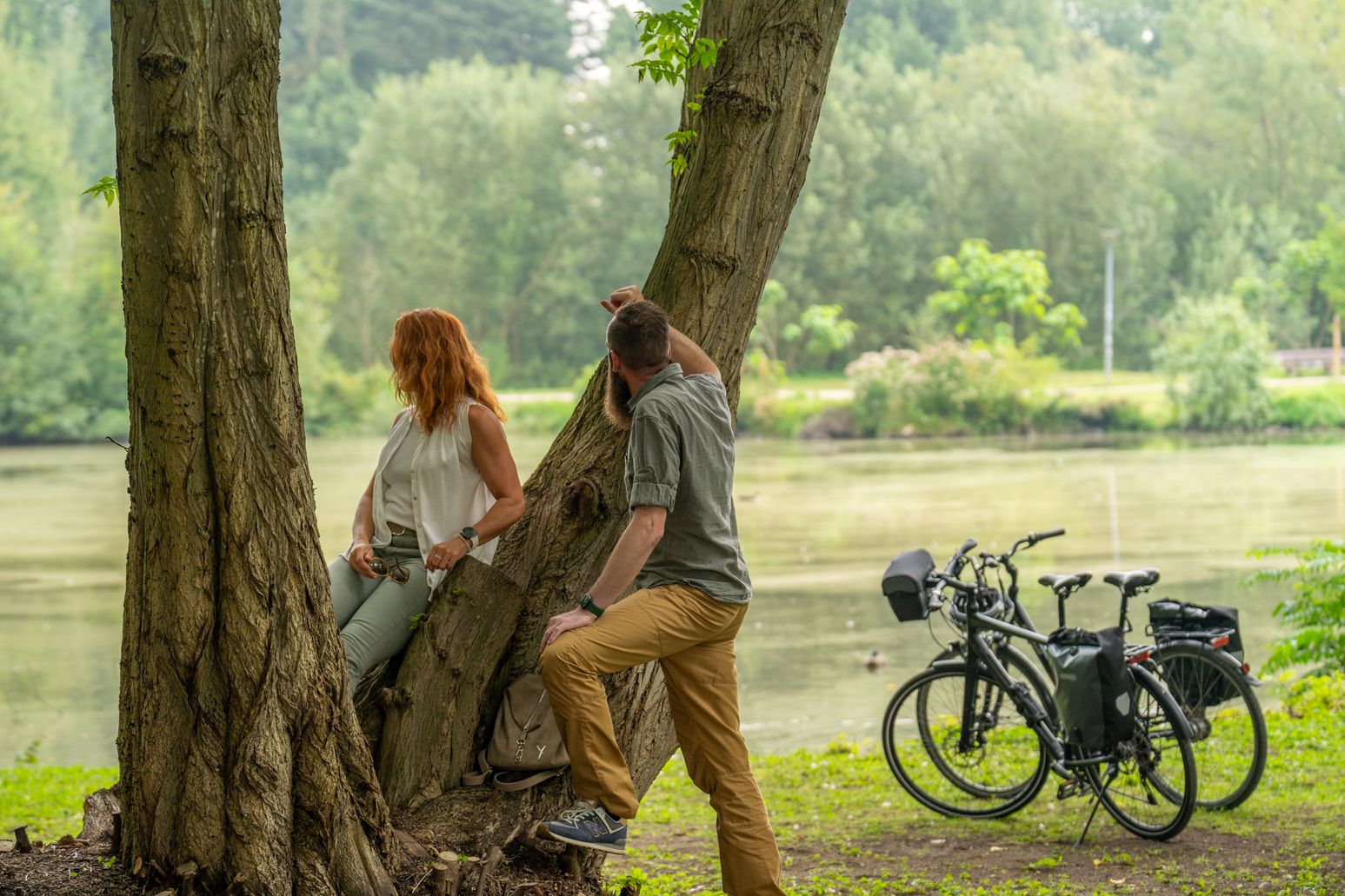 Paar macht eine Fahrradpause und steht am Ufer eines Flusses.