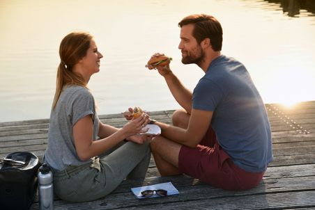 Paar genießt ein Matjesbrötchen bei einer Pause am Glückstädter Hafen bei Abendstimmung.