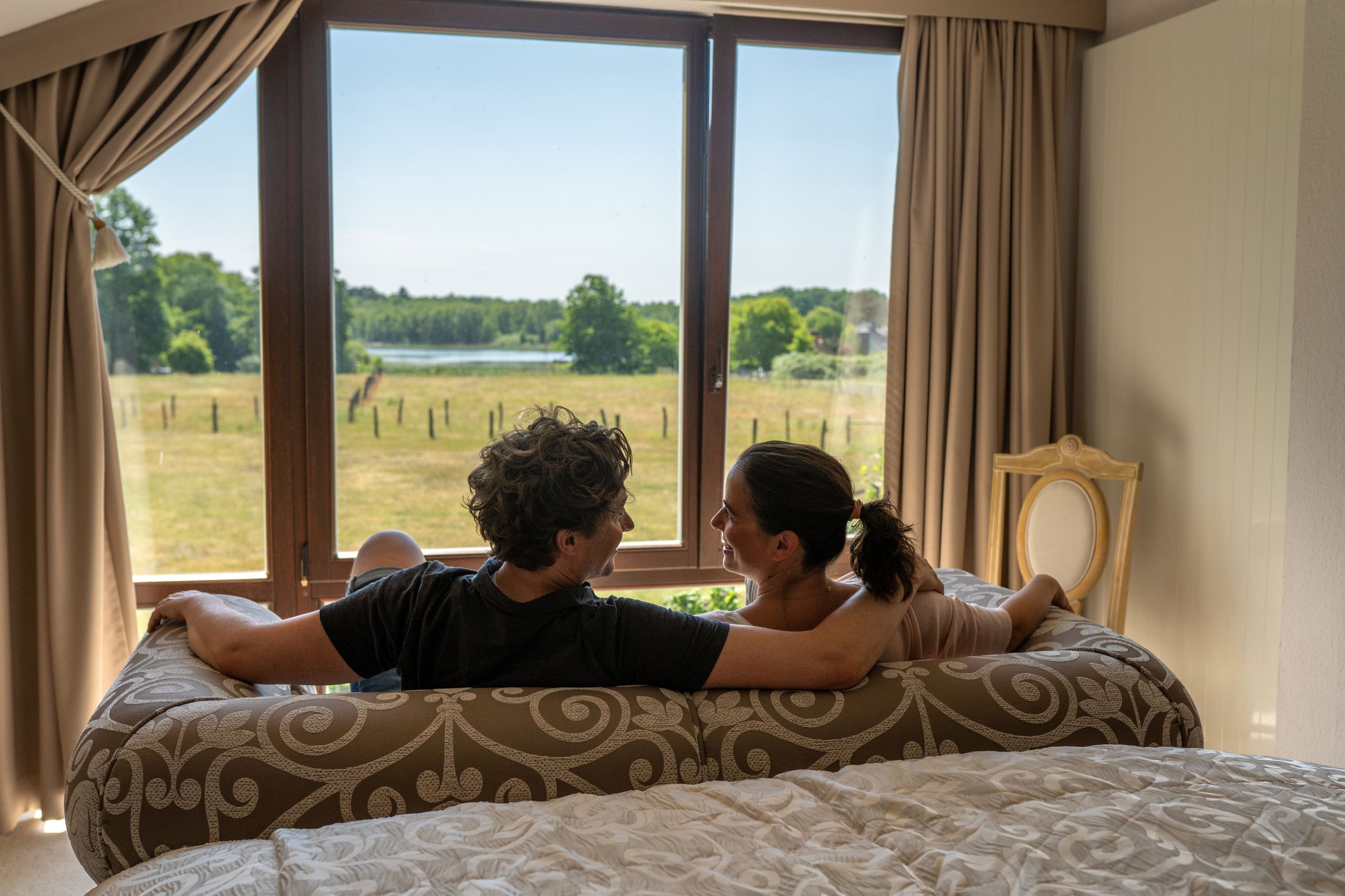 Paar sitzt auf dem Sofa und blickt hinaus in die Naturlandschaft.