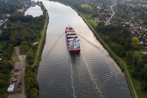 Luftaufnahme vom Nord-Ostsee-Kanal, auf der ein Containerschiff zu sehen ist.