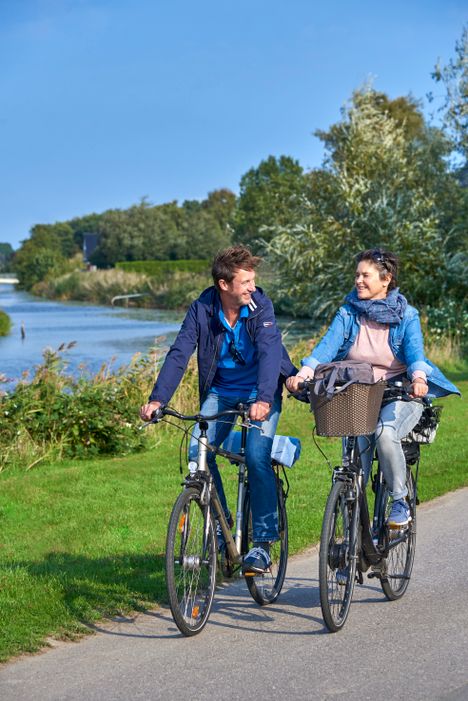 Paar macht eine Fahrradtour am Wasser entlang.