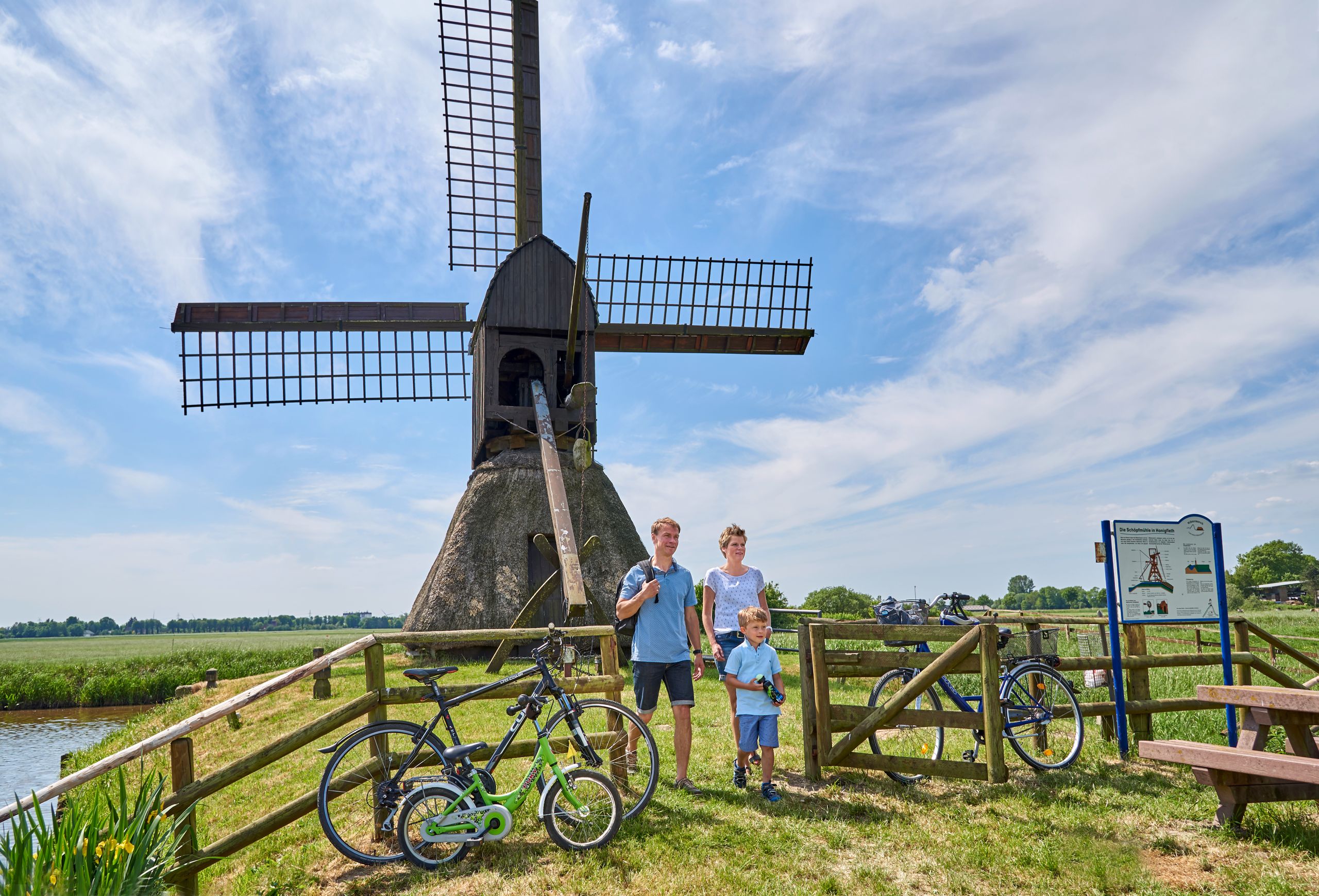 Eine Familie ist mit dem Fahrrad in der Wilstermarsch unterwegs und erkundet die Schöpfmühle Honigfleth. Kreis Steinburg