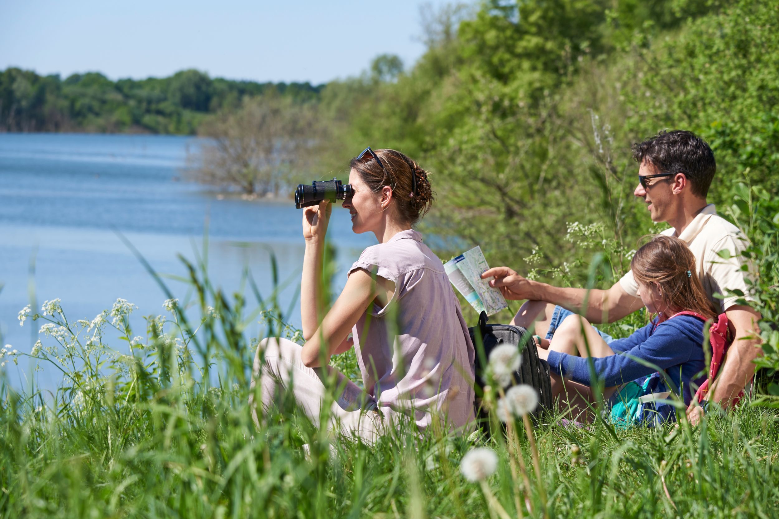 Familie sitzt am Uferrand der Tongrube Muldsberg und genießt den Blick aufs Wasser.